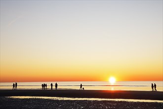 People on the beach at sunset over the North Sea