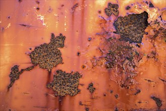 Peeling paint and rust on orange metal wall