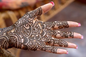 Mehendi tatooed hand of Indian bride on her wedding eve