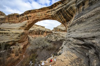 Tourist sits under rock arch