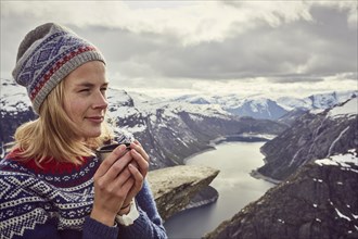 Young woman in Norwegian sweater drinks tea
