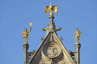 Golden figures with eagle figure on gable of a guild house