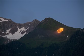 Midsummer Fire on alpine meadow under summit