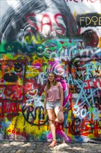 Woman standing in front of colorful graffiti at the John-Lennon-Wall
