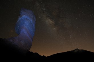 Illuminated Roque Cinchado and Pico del Teide with starry sky