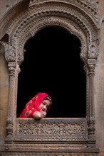 Young girl looking out of a window from an old haveli