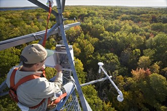Dr. Chris Vogel checks instruments on a 150-foot tower above the forest canopy