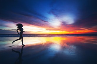 Woman running on beach at sunset