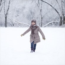 Girl in winter clothes runs across snowy meadow in winter
