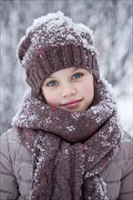 Girl with a snow-covered wool cap in winter