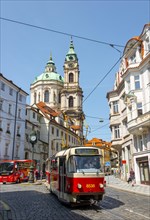 Red tram runs through a street