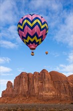 Two hot air balloons fly over Camel Butte