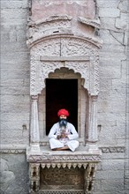 Man practicing yoga in a window at the stepwell Toorji Ka Jhalra Jodhpur