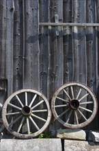 Two old wagon wheels in front of a barn