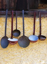 Various ladles hanging on a wall of a farm