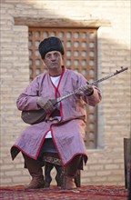 Man in traditional costume playing on the Dombra