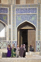 Women in traditional clothing in front of the entrance portal of the Mir-Arab-Madrasa