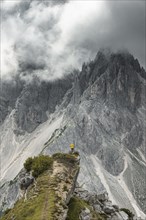 Woman in yellow jacket standing on a ridge