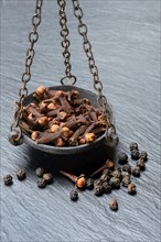 Cloves and peppercorns in a weighing pan