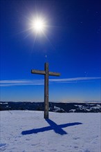 Summit cross in snow with starry sky by moonlight