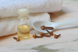 Clove oil in bottles and cloves on towel