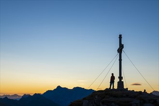 Sunrise with cross of the Thanell summit and mountaineers with Lechtaler Alps