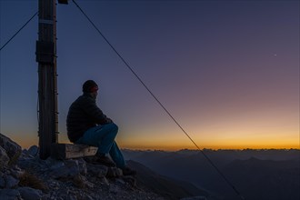 Sunrise over Lechtal Alps with mountaineer and summit cross Ellbogener Spitze