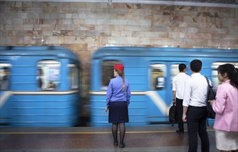 Conductor in uniform and passengers waiting at the passing train