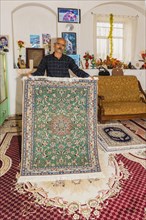Iranian man showing a handmade carpet