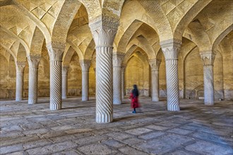Iranian woman walking through the prayer hall with Shabestan pillars