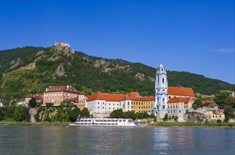 Excursion boat on the Danube in front of the baroque church of Duernstein Abbey