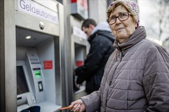 Senior citizen with cash card at ATM looks skeptical