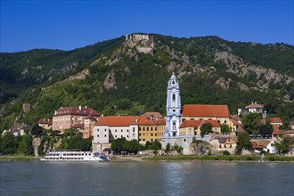 Excursion boat on the Danube in front of the baroque church of Duernstein Abbey