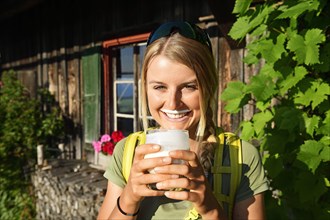 Young female hiker drinks buttermilk at the Kraftalm