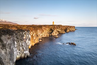 Orange lighthouse of Oendverdarnes stands on cliffs