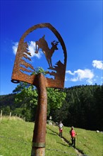 Hikers next to an artistically decorated shovel at the Chiemhauser Alm