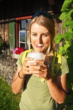 Young female hiker drinks buttermilk at the Kraftalm