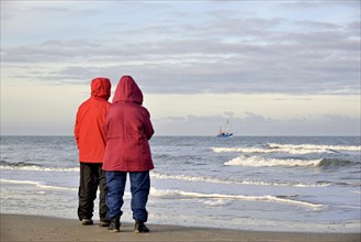Two people on the beach watching a crab cutter off Norderney