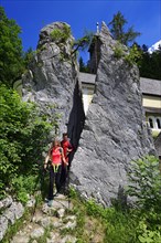 Hikers walk through the split rock at Klobenstein