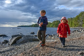 Little girl and boy playing in the open air by a lake