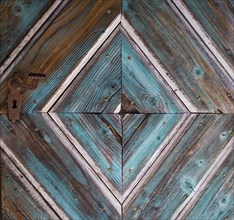 Old wooden house door with diamond-shaped pattern on a historical farmhouse