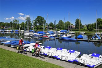 Couple with electric bikes rides in the port of Matzing on Lake Wallersee