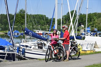 Couple with electric bikes in the port of Matzing on Lake Wallersee