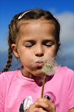 Girl blowing in dandelion