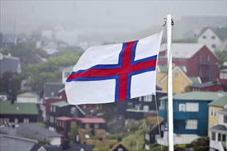 Faroese flag in front of houses in the fog