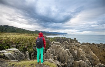 Young woman looking at coastal landscape of sandstone rocks