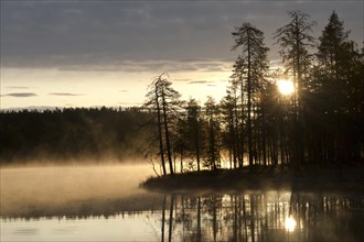 Sunrise with fog at a lake in the Finnish Taiga