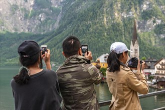 Asian tourists photograph the old town of Hallstatt