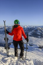 Skier with ski helmet and skis standing at the ski slope