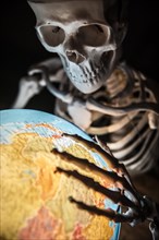 Skeleton with bony hand on globe